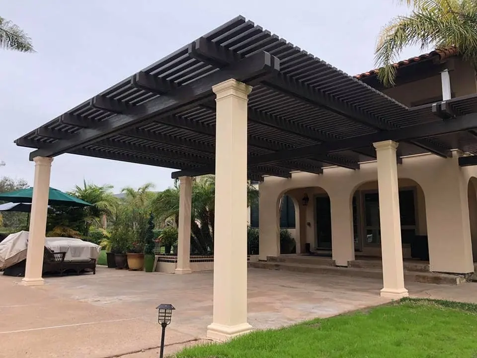 Dark brown lattice patio cover on round columns over a large patio